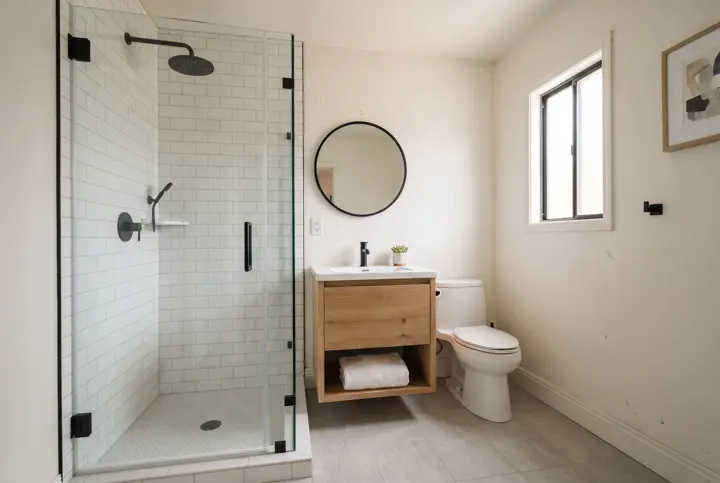 A compact ADU bathroom with a frameless glass walk-in shower with white tile