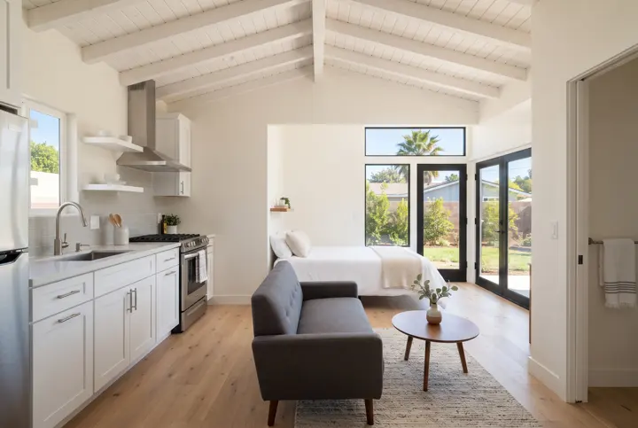 An open-plan ADU interior with a vaulted ceiling with a white-painted wood beam