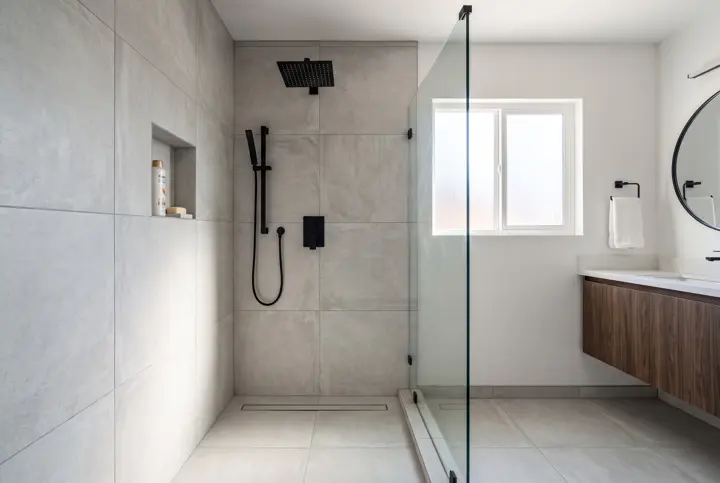 Curbless walk-in shower with large-format gray tile, a linear drain and matte black fixtures