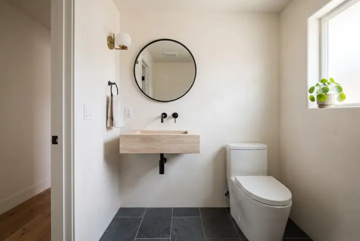 A small powder room with smooth warm-white plaster walls and ceiling