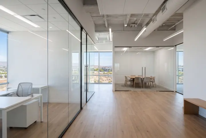 A tenant office suite interior with frameless glass partition walls creating private offices