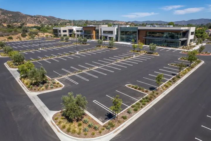 Aerial view of a freshly paved and striped parking lot with landscaped islands at an office complex