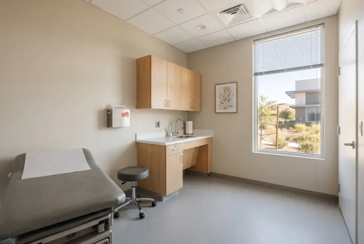 A medical exam room with a padded exam table with a white paper-free vinyl surface
