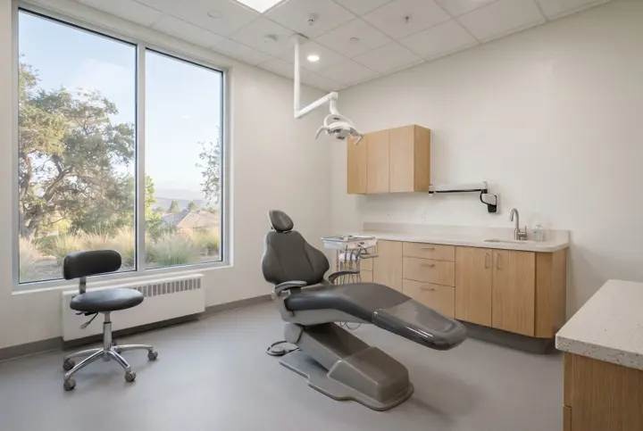 A dental treatment room with a modern reclined dental chair with an overhead operatory light