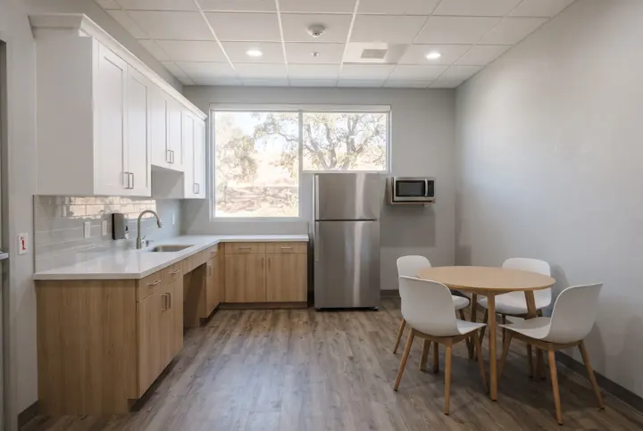 A renovated employee break room with new white and light-wood cabinets