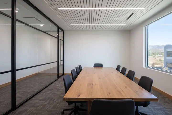 A renovated conference room with a full glass partition wall with thin black frames