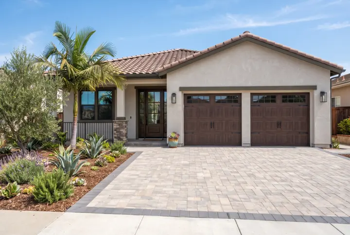 A interlocking paver driveway in light gray and tan with a contrasting dark border band