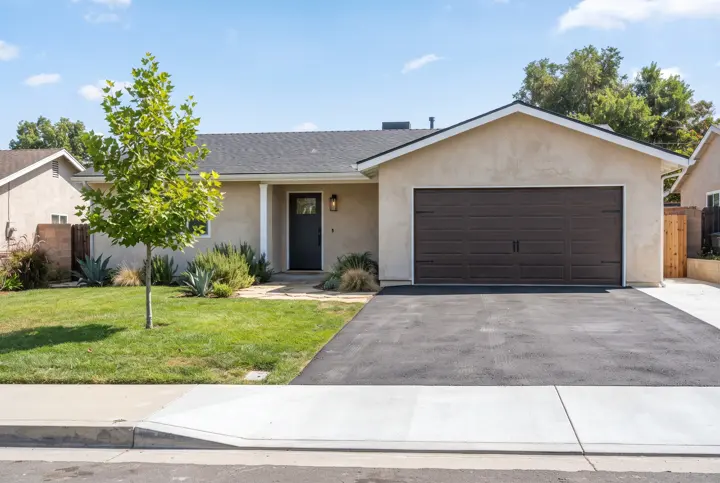 A fresh charcoal asphalt driveway with a smooth light-gray concrete apron at the street and clean straight edges