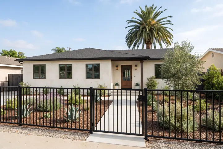 A black powder-coated metal picket fence with a matching pedestrian gate along the front yard of a stucco home