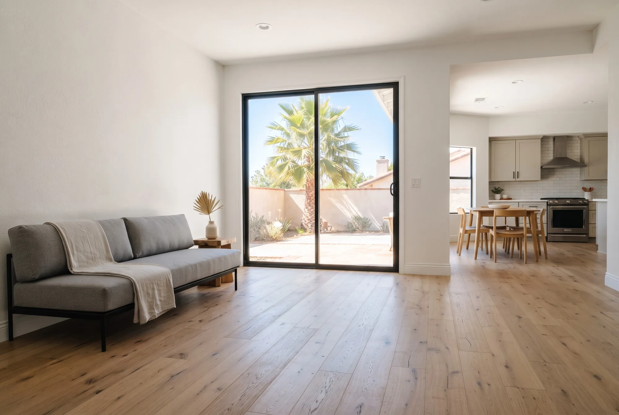 An open living room with wide-plank light natural oak flooring, white plaster walls