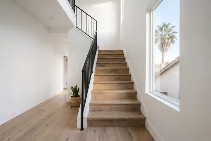 A straight staircase with natural oak treads and white-painted risers, a slim black metal railing