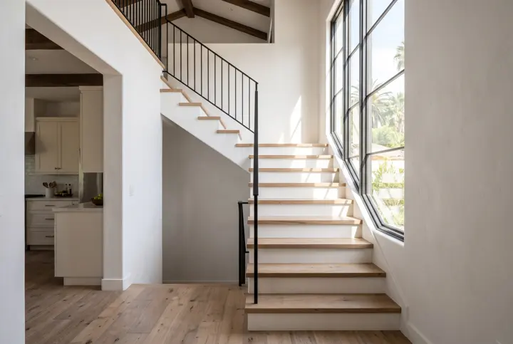 Staircase with oak treads, a black metal railing and a tall window