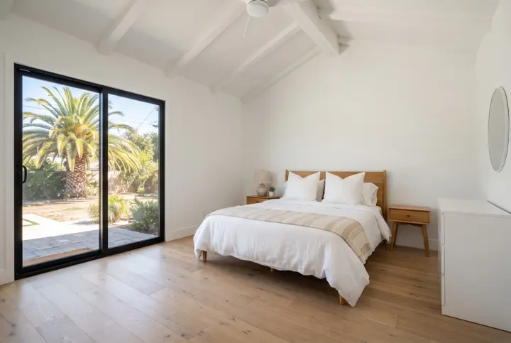 A primary bedroom with a vaulted ceiling with a white-painted wood beam
