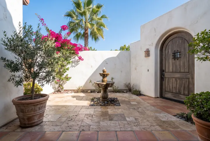 A Spanish-style courtyard with a small tiered stone fountain in the center