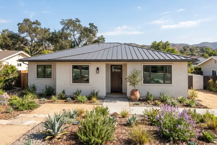 A modern single-story stucco home with a new charcoal-gray standing-seam metal roof with crisp straight seams and a clean ridge