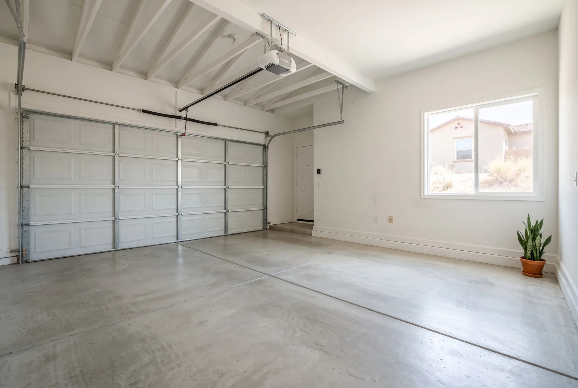 The interior of a clean residential two-car garage with a polished sealed light-gray concrete floor with a subtle sheen