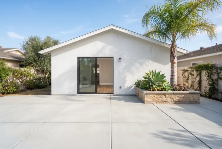A new light-gray backyard patio concrete slab with clean saw-cut control joints in a square grid