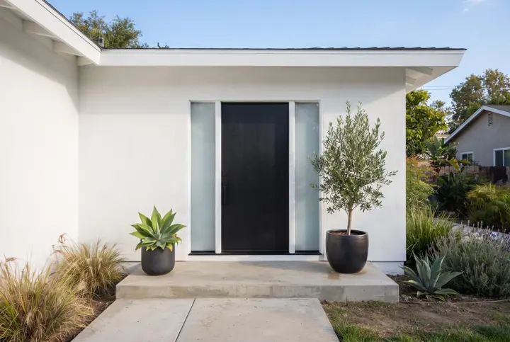 A modern solid matte black entry door with two narrow full-height frosted-glass sidelights (no reflections in the glass)
