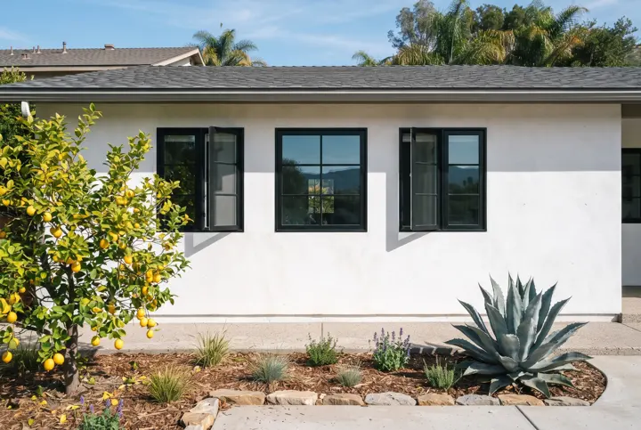 A row of three black-framed casement windows on a smooth white stucco wall of a Southern California home
