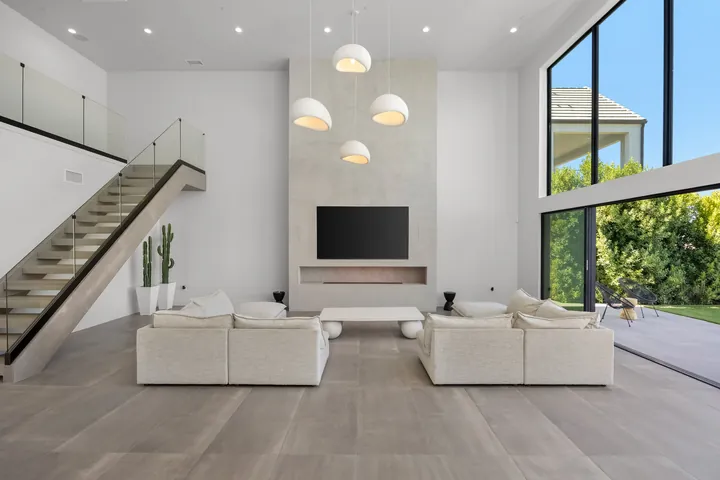Double-height great room with a glass-railed staircase and fireplace wall, interior design and renovation in Santa Clarita, CA, photo 1