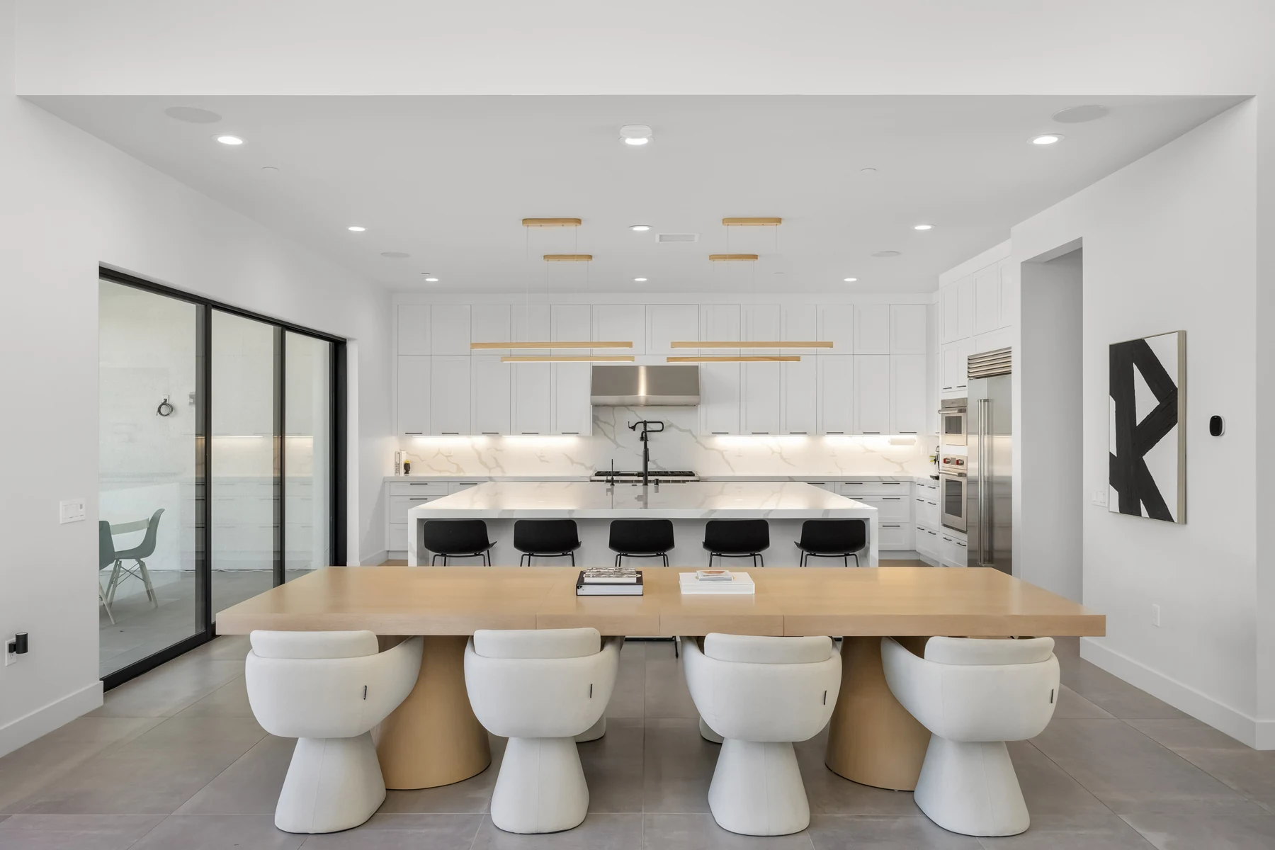 Open kitchen and dining area with a large stone island and a long wood dining table, kitchen renovation in Santa Clarita, CA