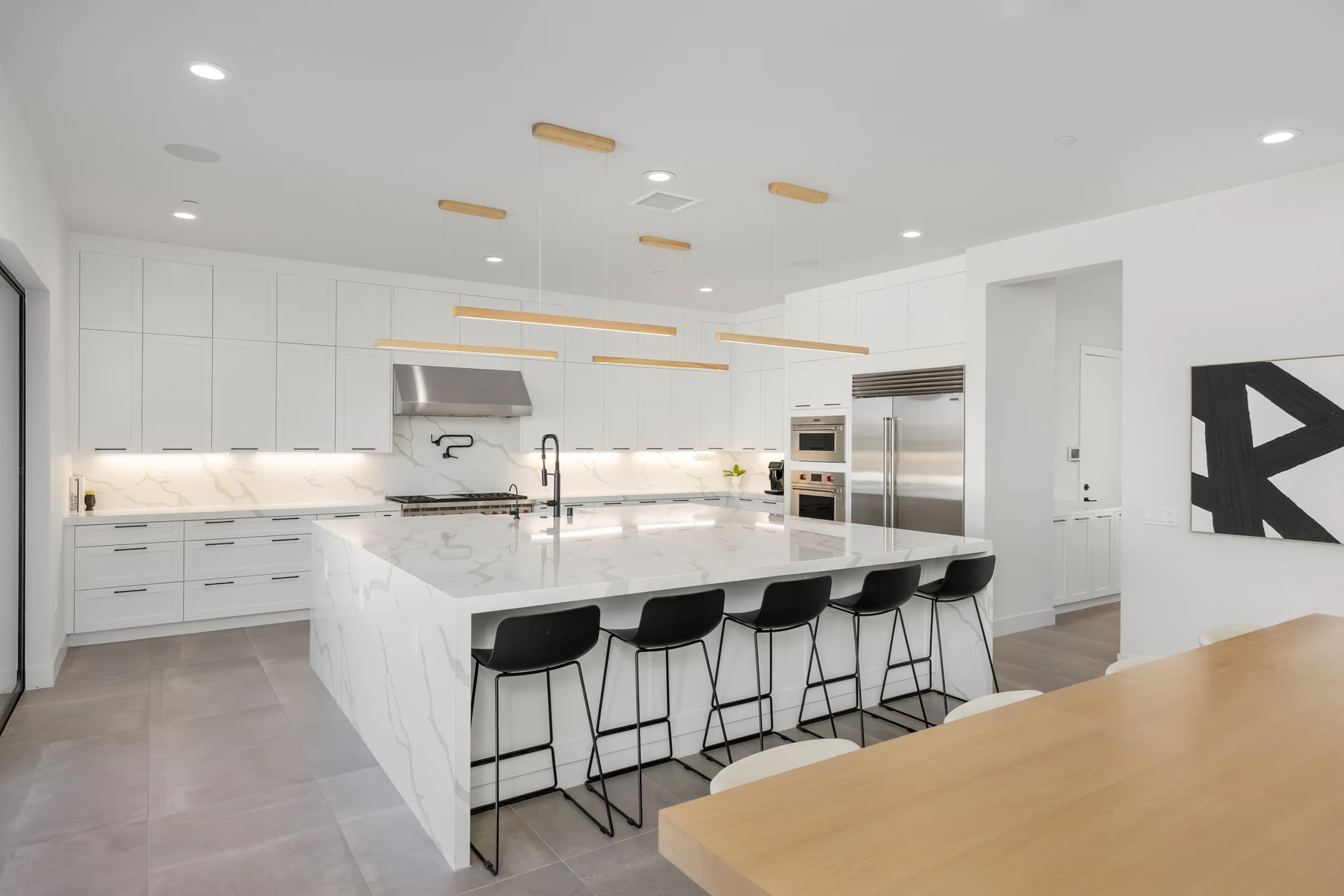 Chef's kitchen with a large white stone island and bar stools in a luxury remodel in Santa Clarita