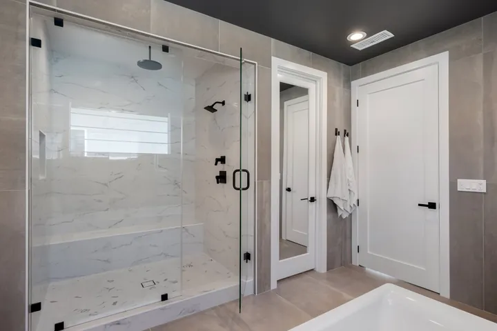 Frameless glass walk-in shower with marble-look tile and black fixtures, bathroom renovation in Santa Clarita, CA, photo 20