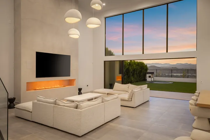Great room at dusk with a linear fireplace, wall-mounted TV and cream sectional, interior design and renovation in Santa Clarita, CA, photo 4
