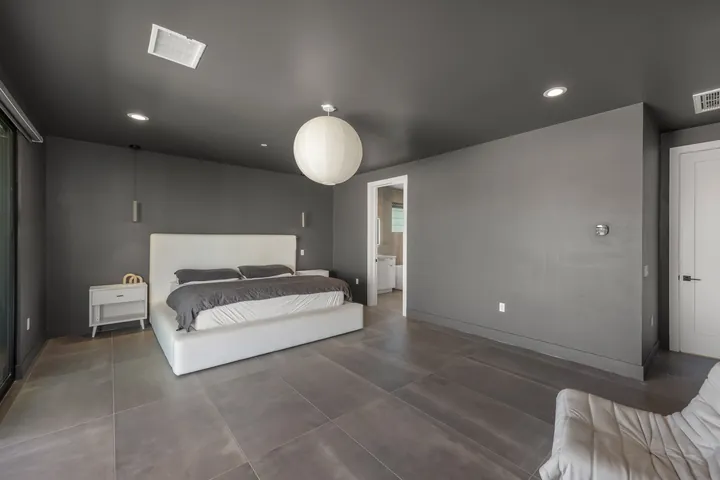 Primary bedroom with charcoal accent walls, a white upholstered bed and a paper lantern pendant, interior renovation in Santa Clarita, CA, photo 15