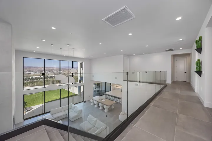 Upper hallway with a glass railing overlooking the great room and a large window with valley views, interior design in Santa Clarita, CA, photo 26