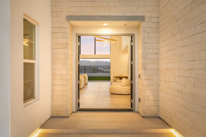 Front entry with a glass-and-steel door and light stone walls opening to the great room, interior renovation in Santa Clarita, CA, photo 32
