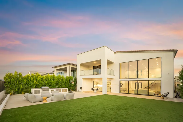 Rear of the home at sunset with a wall of glass, balcony and lawn, Santa Clarita, CA, interior renovation by MSH Development, photo 35